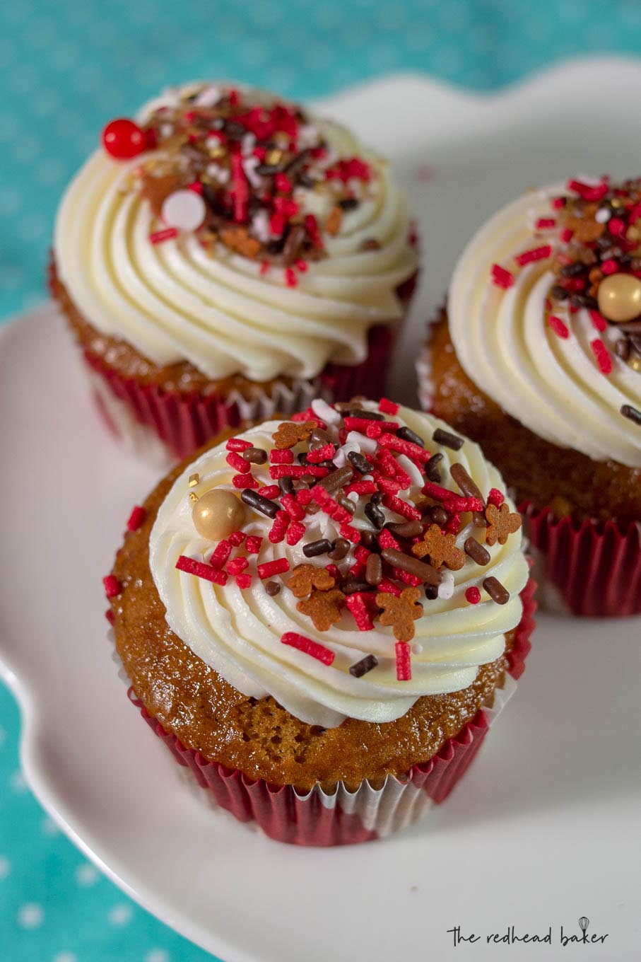 Three gingerbread cupcakes on a white cake stand