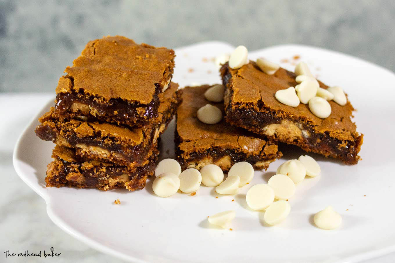 Five gingerbread white chocolate blondies on a mini cake plate with white chocolate chips