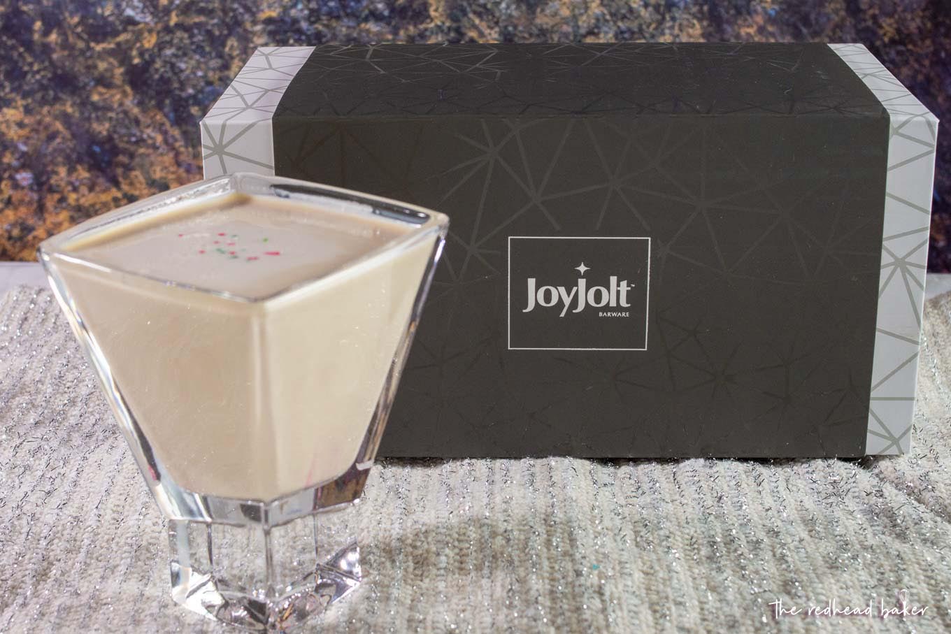 A sugar cookie martini in front of a box of Joy Jolt glassware