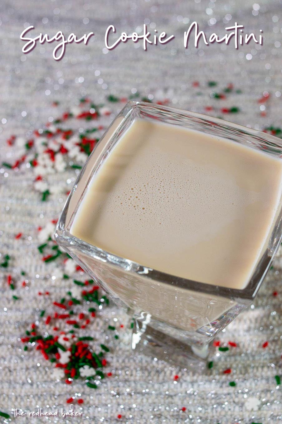 A sugar cookie martini sitting amongst snowflake sprinkles