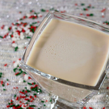 A sugar cookie martini sitting amongst snowflake sprinkles