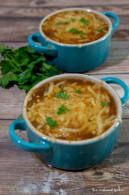 Two cocettes of French onion soup with a bunch of parsley on the side