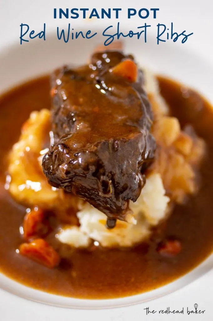 A close up of a bowl of mashed potatoes with a short rib on top surrounded by a pool of gravy