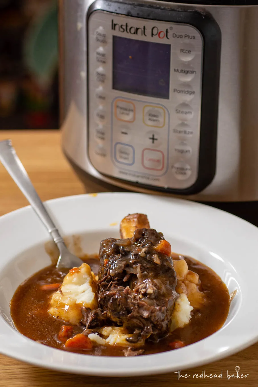 A bowl of short ribs and mashed potatoes in front of an Instant Pot.