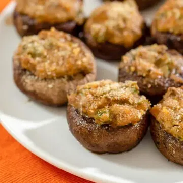 Several jalapeno popper stuffed mushrooms on a white plate.