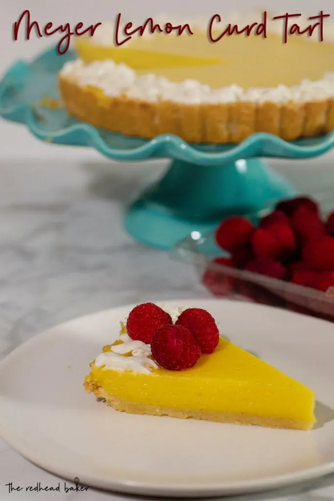 A slice of meyer lemon curd tart on a plate, garnished with whipped cream and raspberries