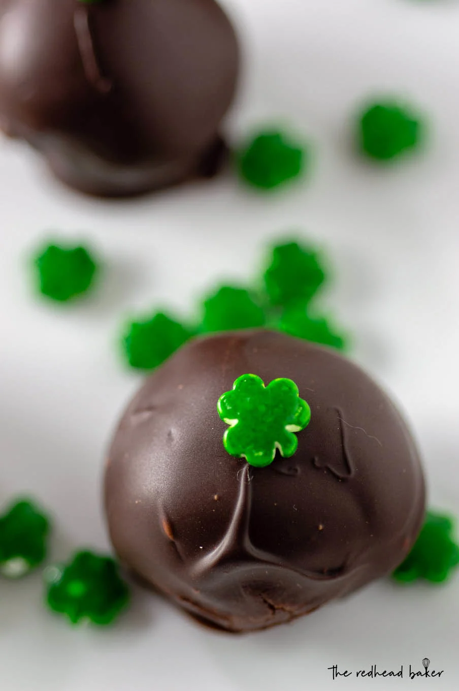 A close-up photo of an Irish cream truffle topped with a shamrock sprinkle.