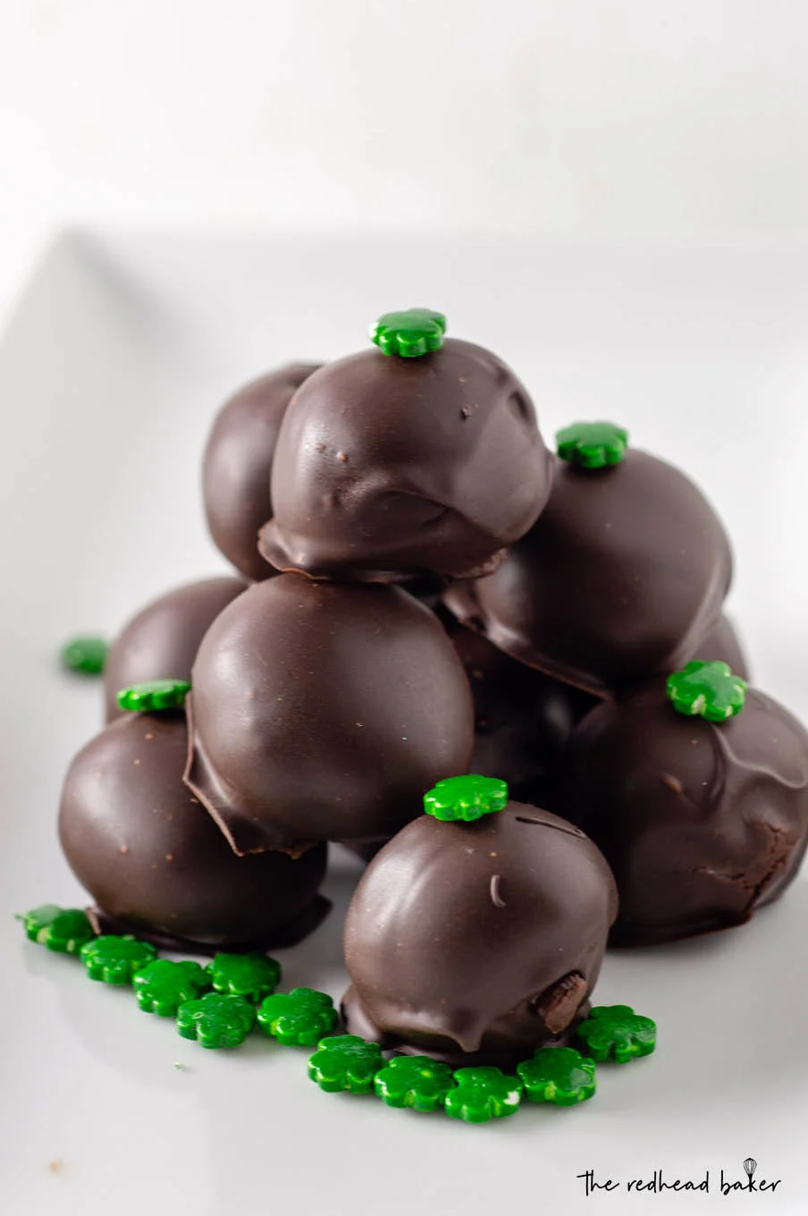 A pile of Irish cream truffles on a white serving tray.