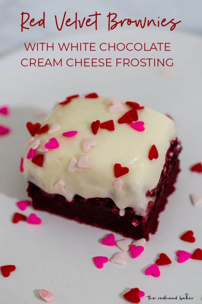 A red velvet brownie on a white plate with heart-shaped sprinkles