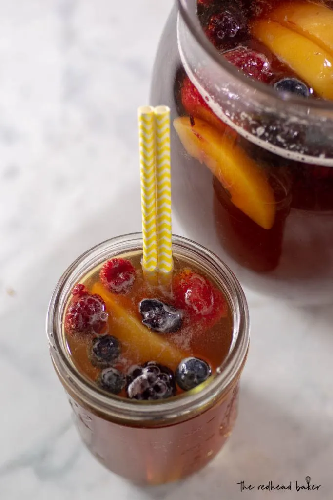 An overhead shot of a mason jar of sangria, with the pitcher nearby