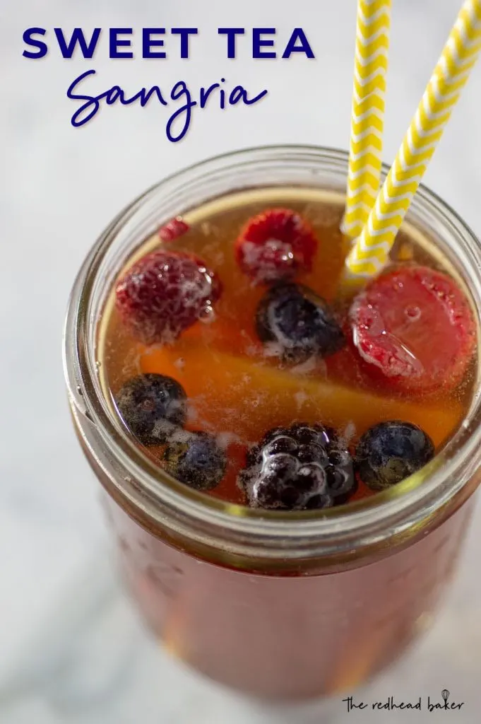 An overhead shot of a mason jar of sweet tea sangria, with two yellow-and-white striped paper straws