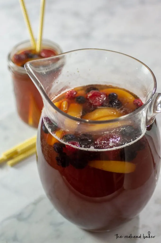 A pitcher of sweet tea sangria with a mason jar of sangria in the background