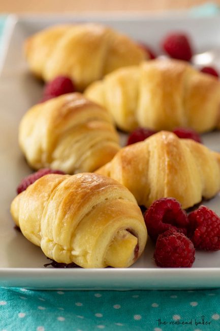 A serving tray of raspberry brioche crescents and fresh raspberries