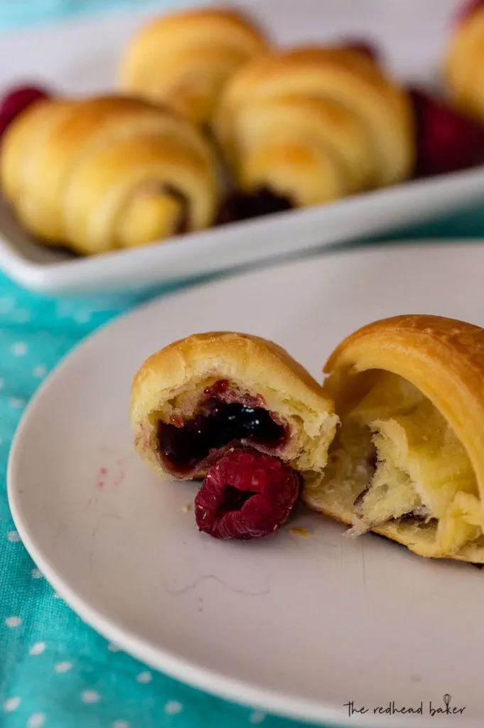 A raspberry brioche crescent broken in half to reveal the raspberry filling