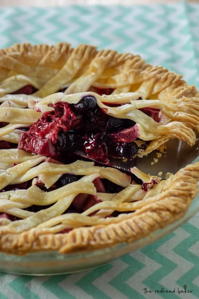 A slice of rhubarb berry pie being lifted out of the baking dish