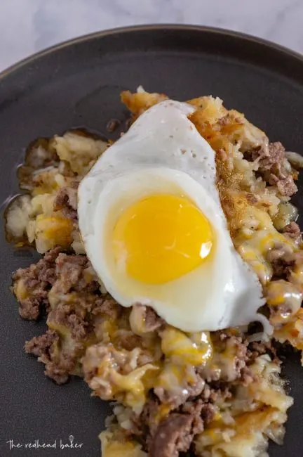 A plate of breakfast poutine topped with a fried egg
