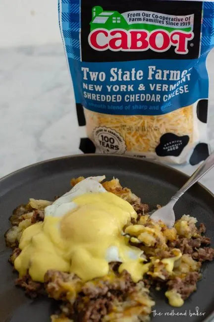 A plate of breakfast poutine in front of a bag of Cabot shredded cheddar cheese