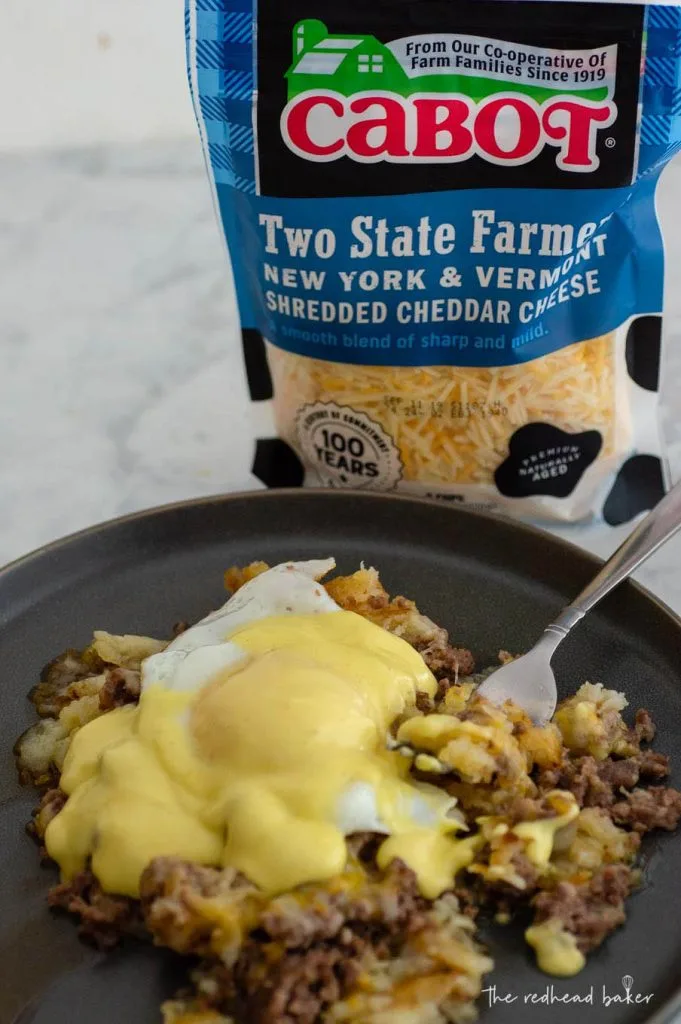 A plate of breakfast poutine in front of a bag of Cabot shredded cheddar cheese