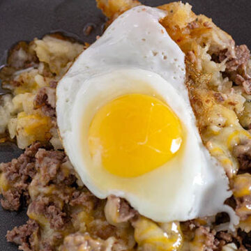 A plate of breakfast poutine topped with a fried egg