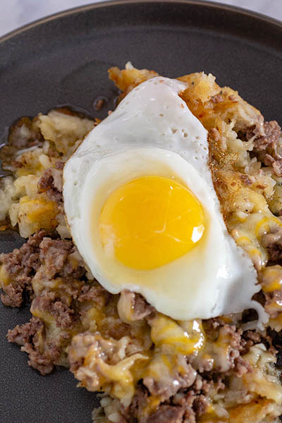 A plate of breakfast poutine topped with a fried egg