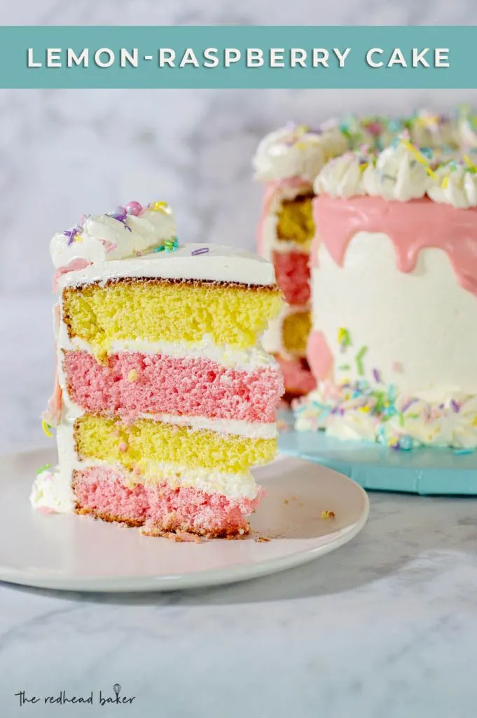A slice of lemon-raspberry layer cake on a plate in front of the rest of the cake