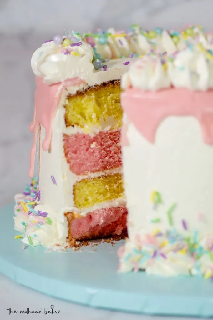 A lemon-raspberry layer cake on a serving board with one slice removed