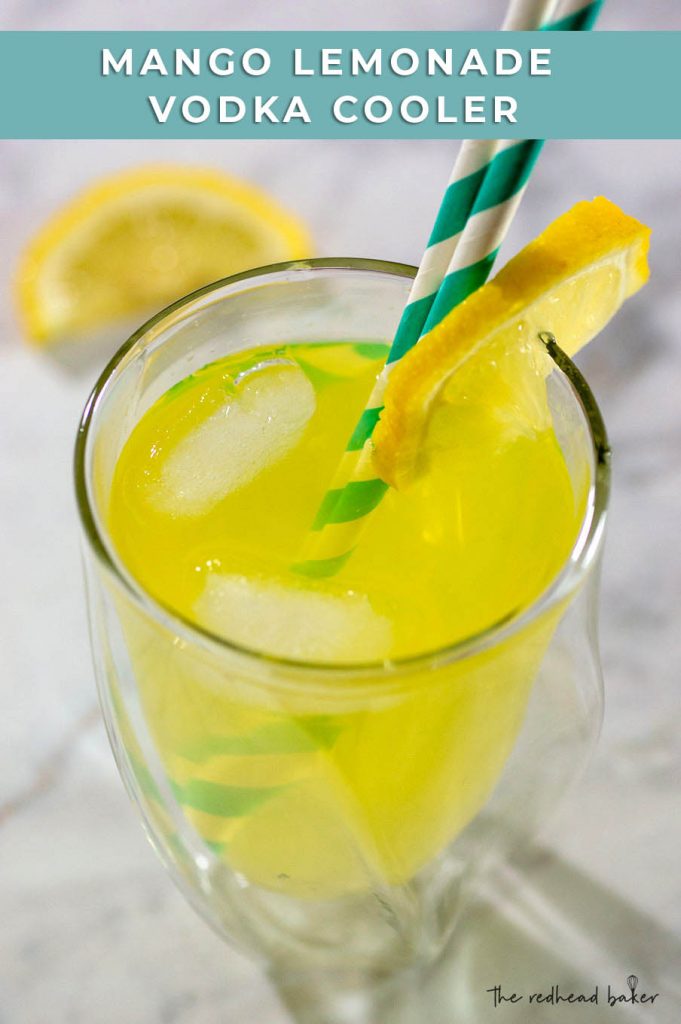 A glass of mango lemonade vodka cooler with ice and a slice of lemon