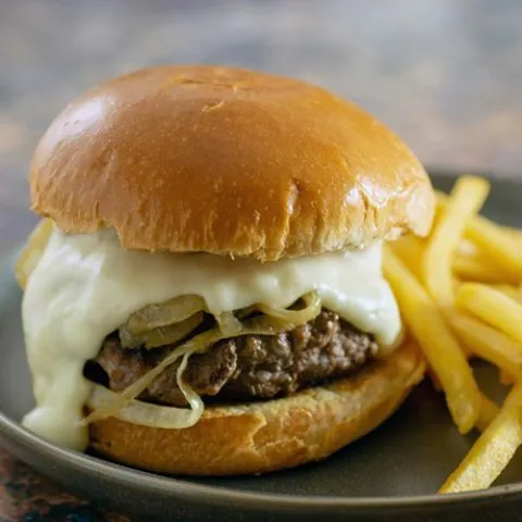 A Philly Burger on a black plate with fries