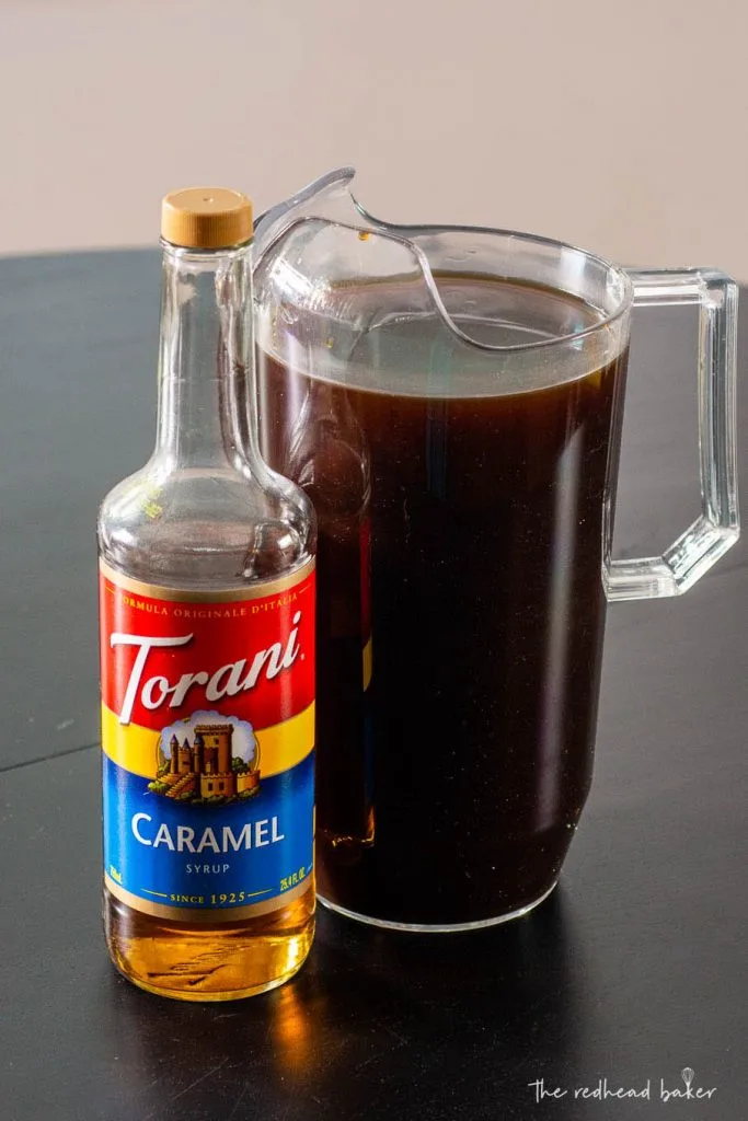 A pitcher of caramel cold brew and a bottle of Torani caramel syrup