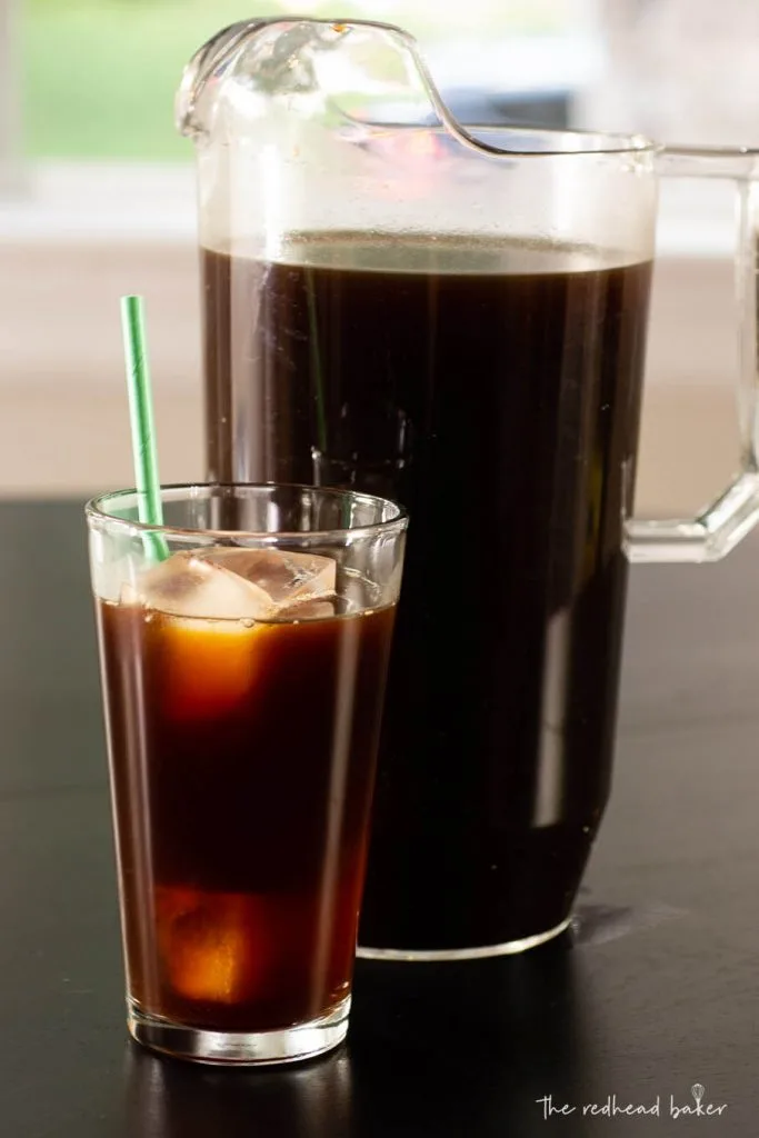 A glass of caramel cold brew in front of a pitcher