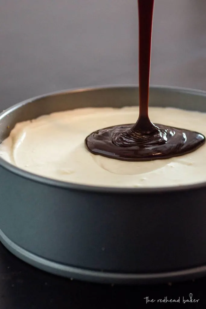 Chocolate ganache being poured onto a smores cheesecake