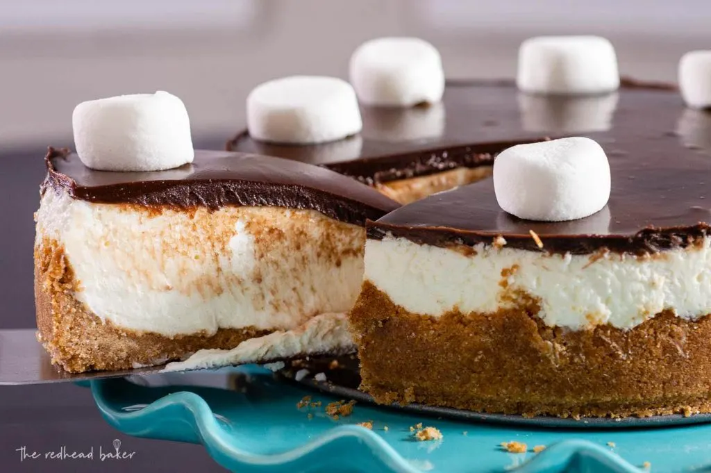 A sliced being pulled out from a smores cheesecake