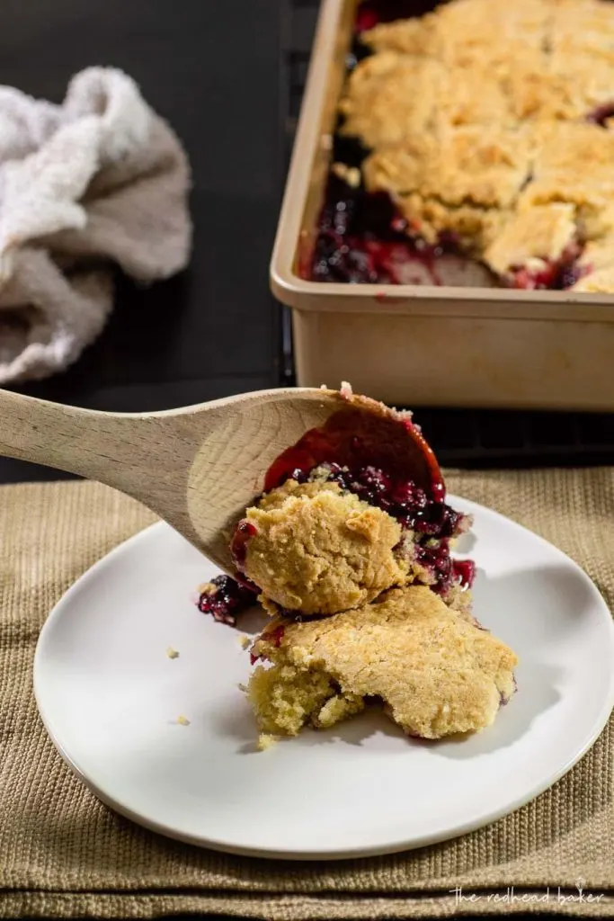 Mixed berry cobbler being spooned onto a plate