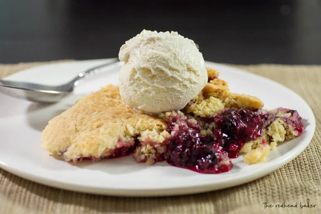 A plate of mixed berry cobbler with a scoop of vanilla ice cream