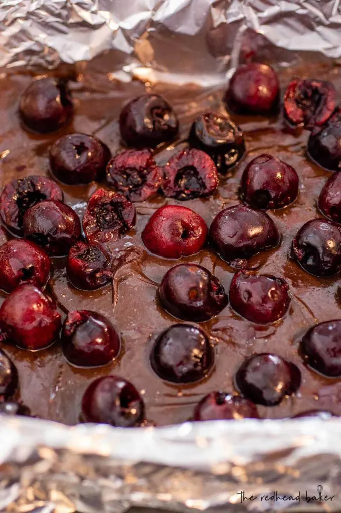 A baking pan of brownie batter with cherries mixed in