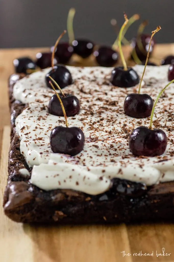 An uncut sheet of black forest brownies topped with fresh cherries