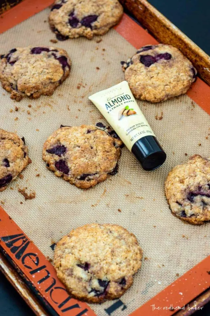 Baked scones on a baking sheet with a tube of Taylor and Colledge almond extract paste