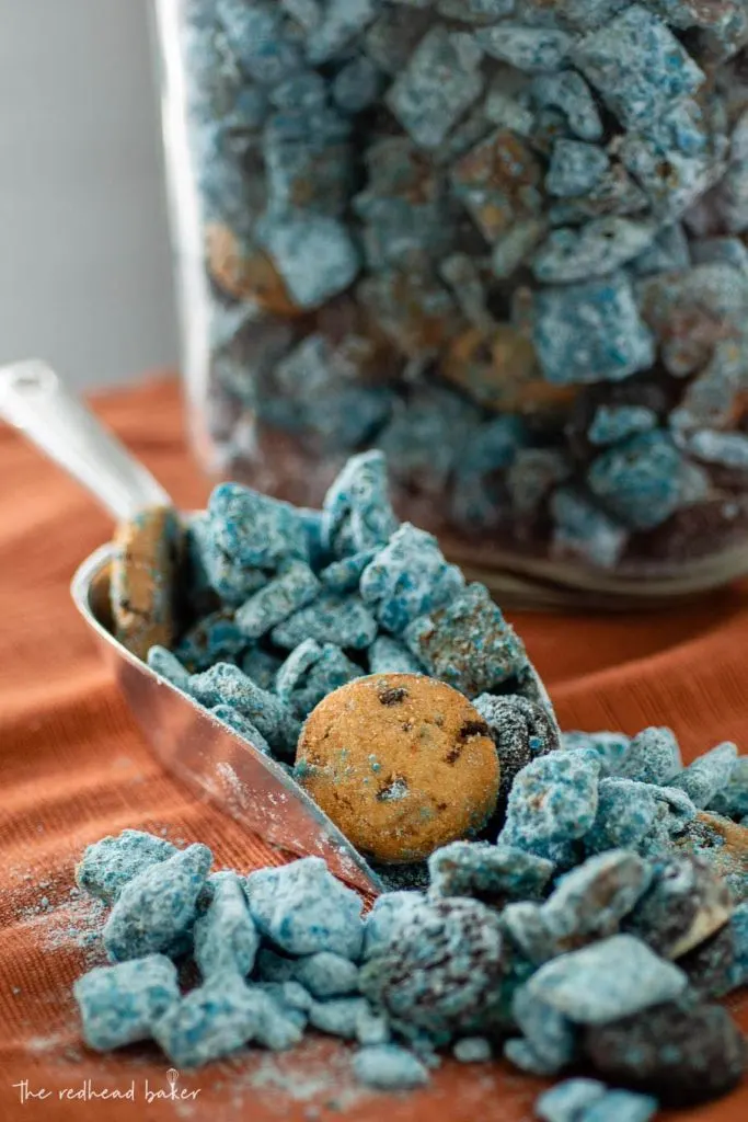 A scoop of Cookie Monster muddy buddies in front of a jar of the snack