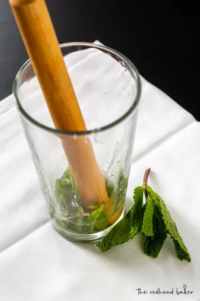 A wooden stick muddling mint and lime juice