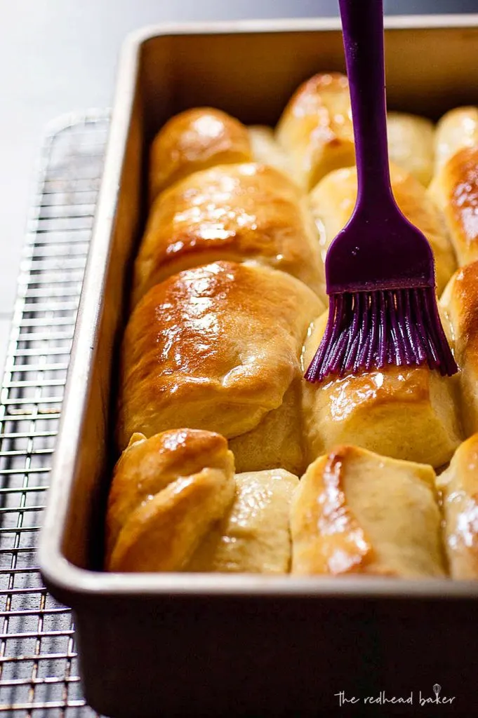 Baked Parker House rolls being brushed with melted butter