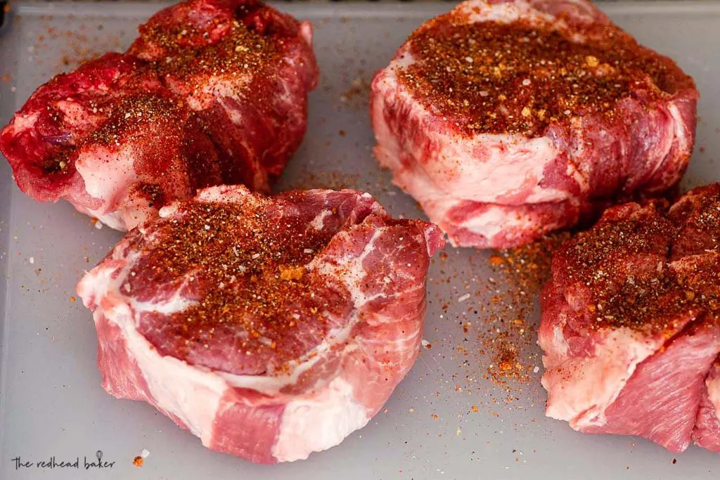 Four pieces of pork shoulder coated in a spice rub