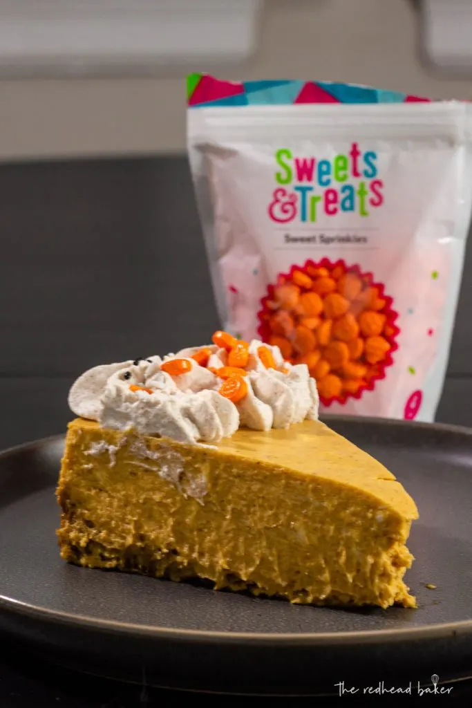 A slice of pumpkin whipped cream in front of a bag of Sweets and Treats pumpkin candy sprinkles