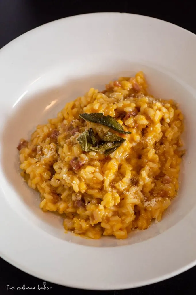 A dish of pumpkin pancetta risotto topped with fried sage