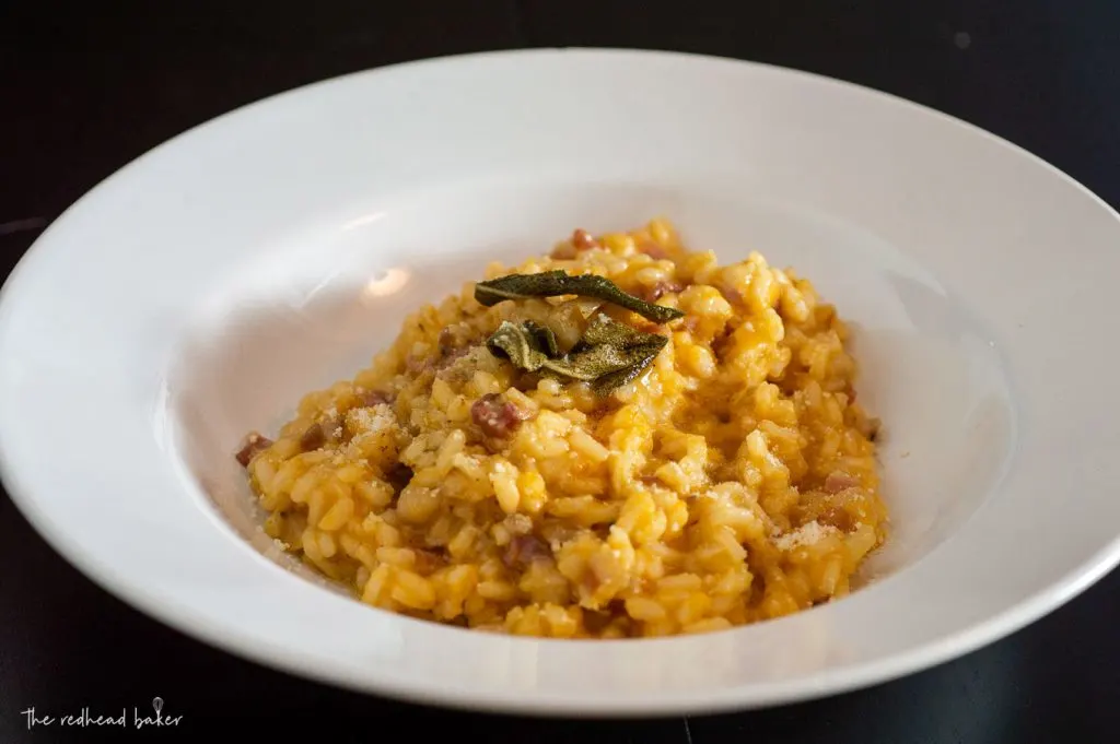 A dish of pumpkin pancetta risotto with fried sage