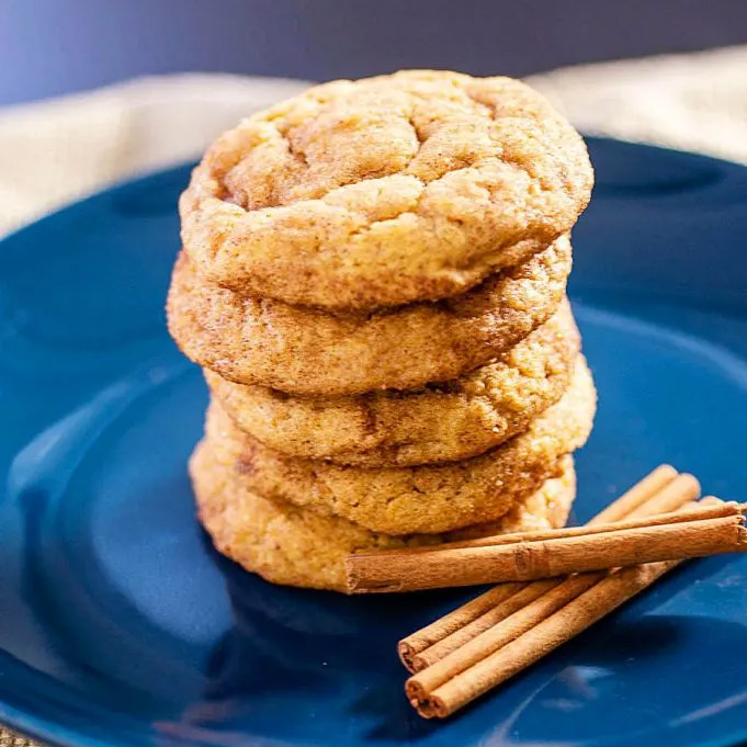 Five snickerdoodle cookies stacked on a blue plate.