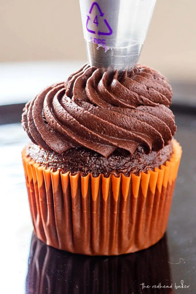 Chocolate kahlua buttercream being piped onto a chocolate cupcake