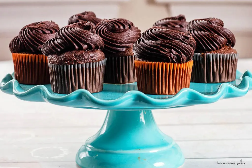 Six chocolate cupcakes on a blue cake stand