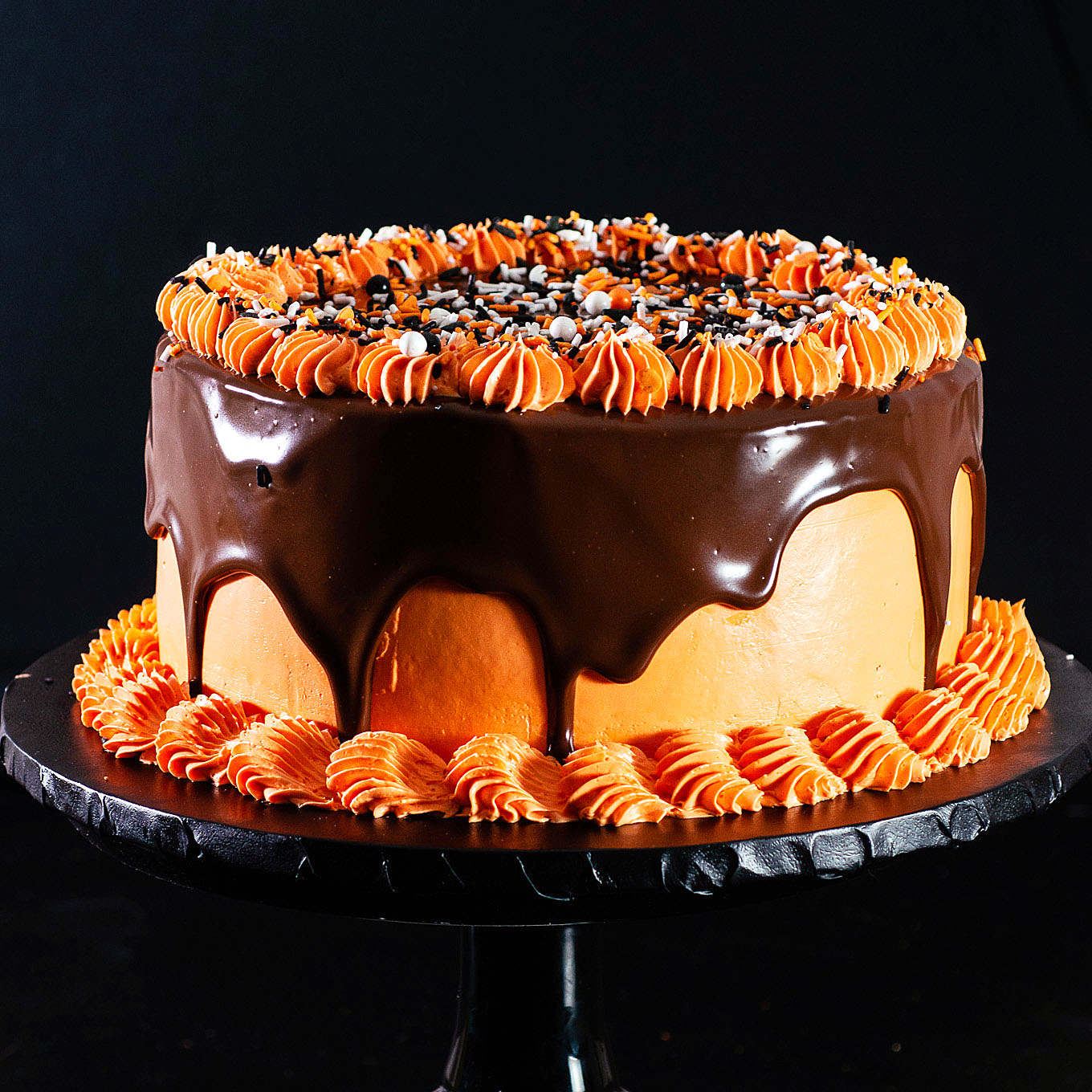 Halloween layer cake on a black cake stand.
