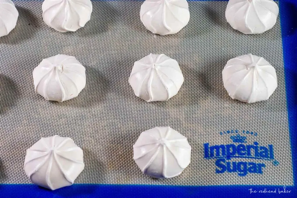 Three rows of baked meringue cookies on a baking sheet