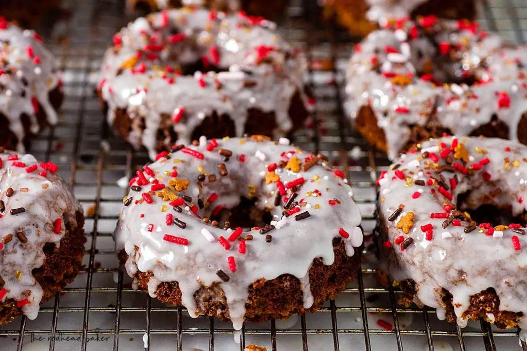 A wire rack of iced baked gingerbread donuts